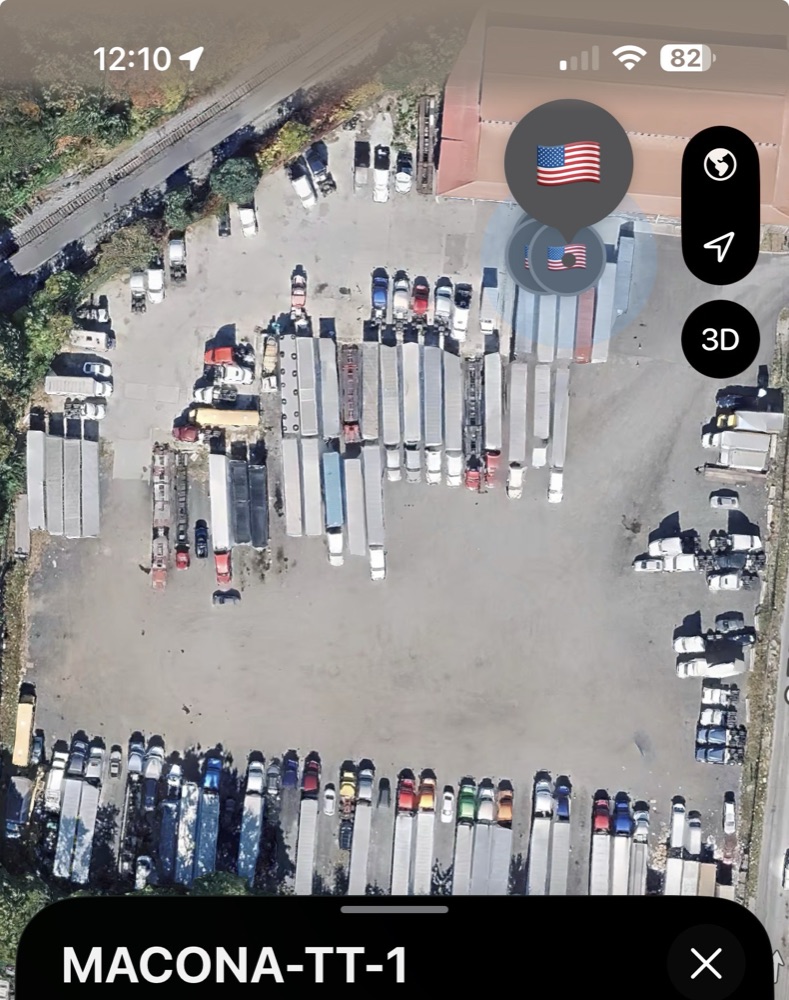 Wider warehouse view showing trackers across multiple containers staged for shipment.