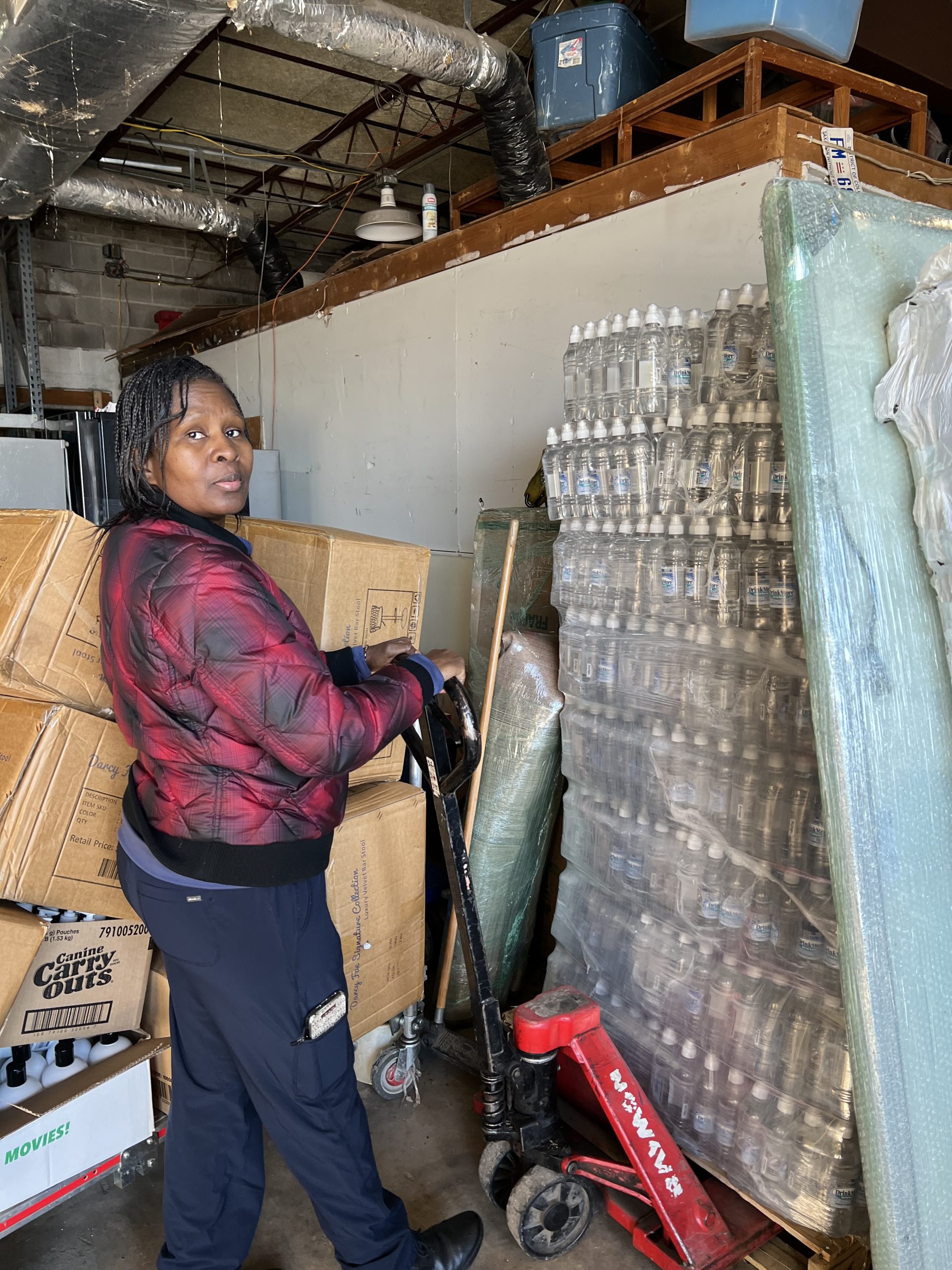 MACONA volunteer with pallets of water bottles in warehouse ready for shipment