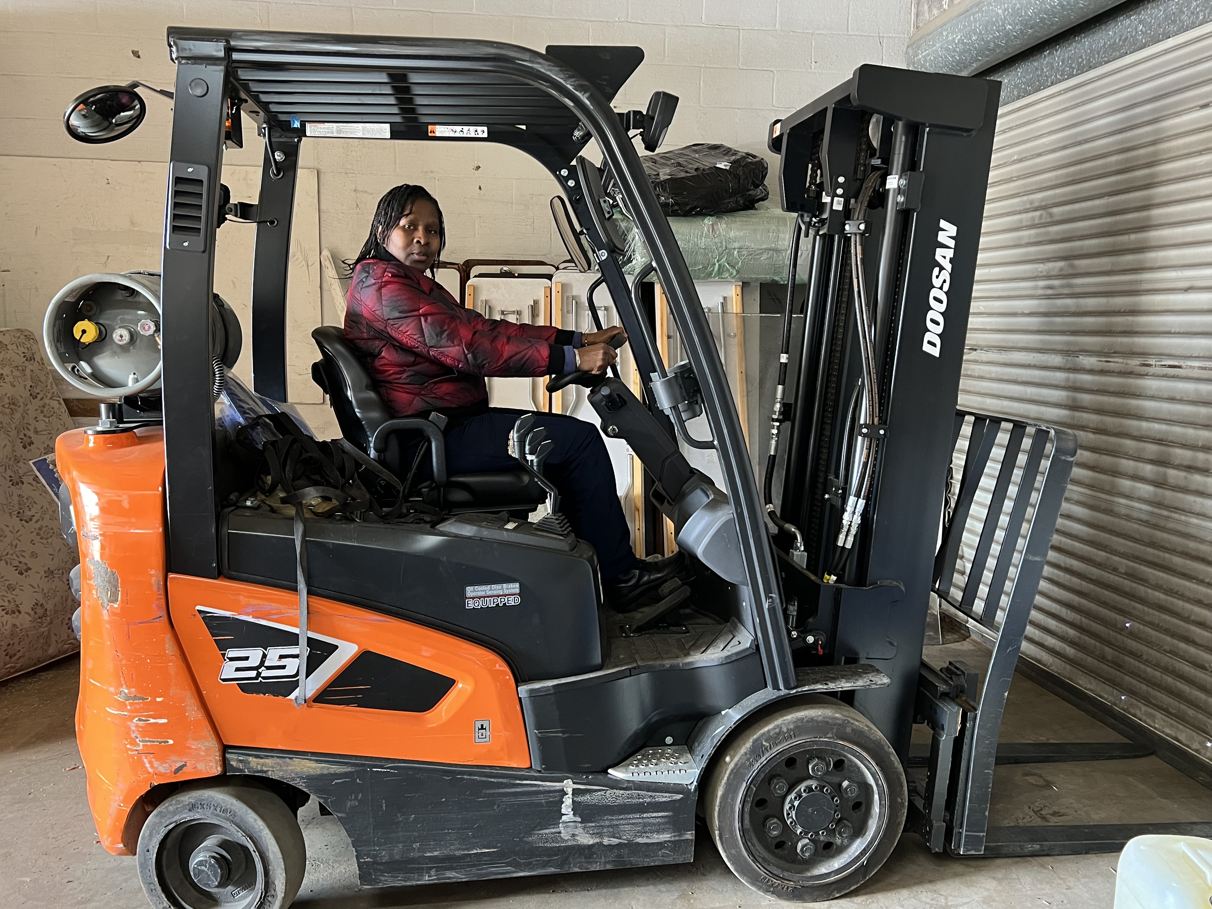 MACONA CEO Mimi Williams operating a forklift while preparing donated goods for shipment