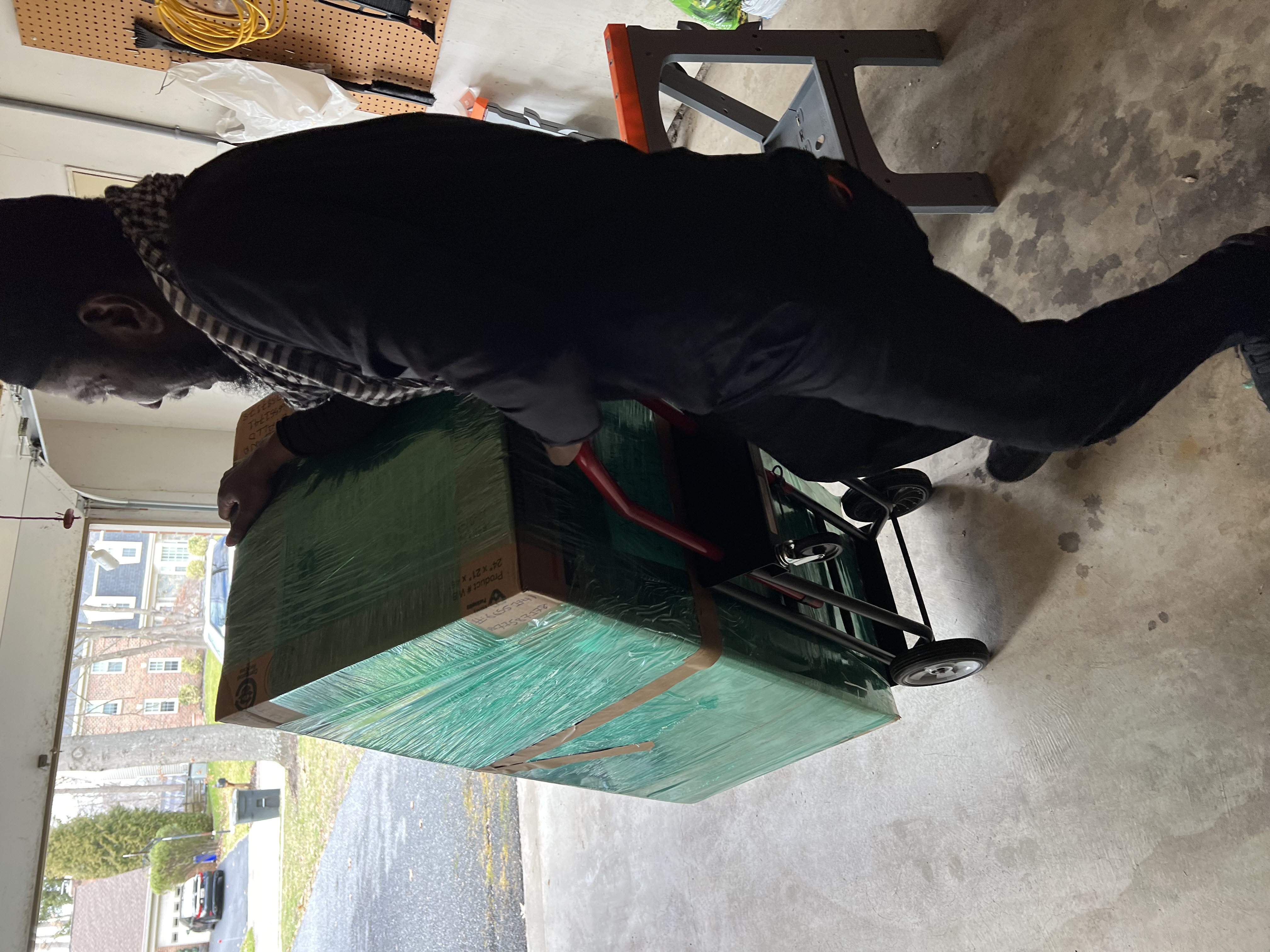 Volunteer lifting and balancing a large donation box onto a dolly