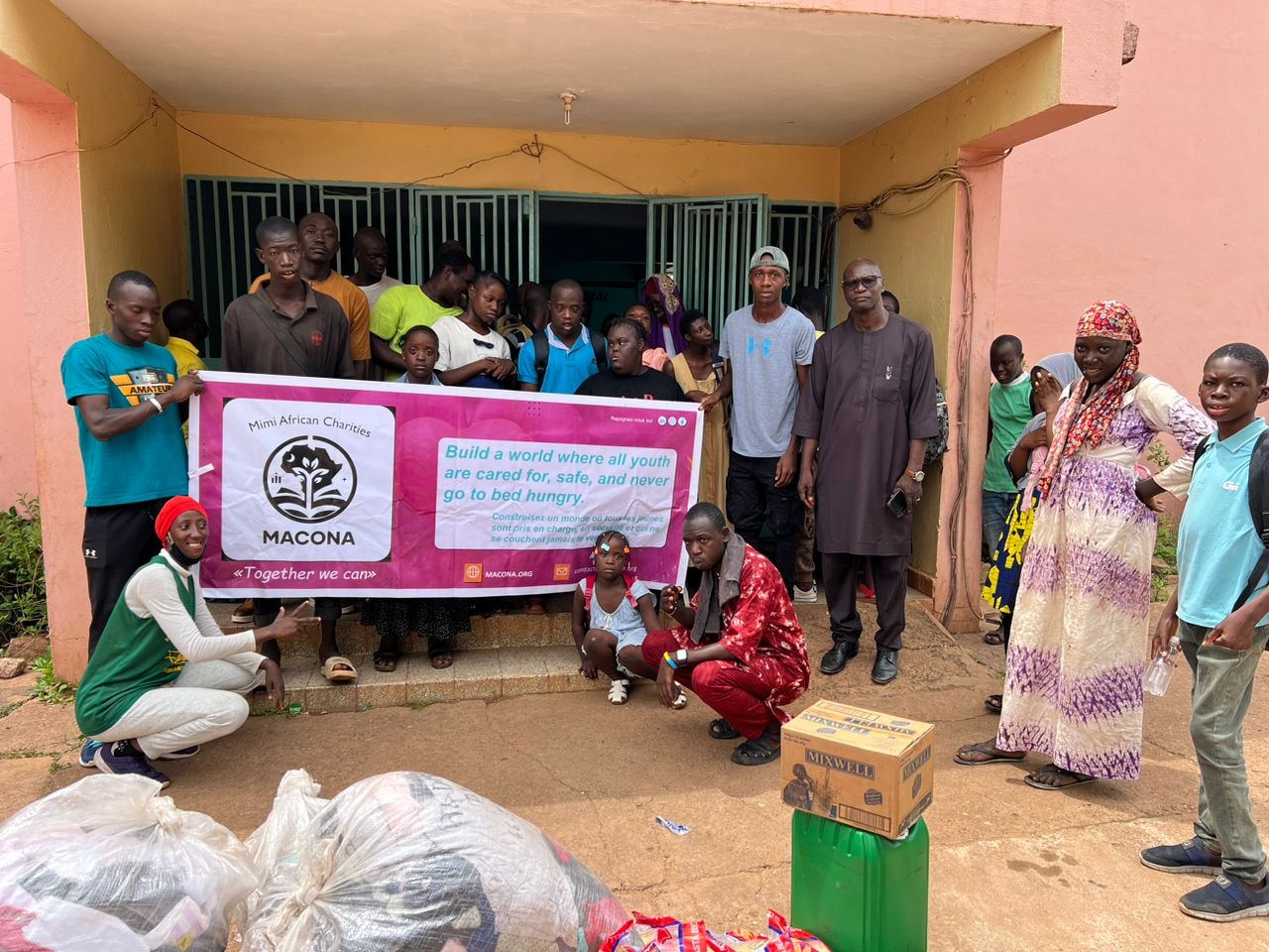 Group photo at the orphanage with MACONA clothes and food banner