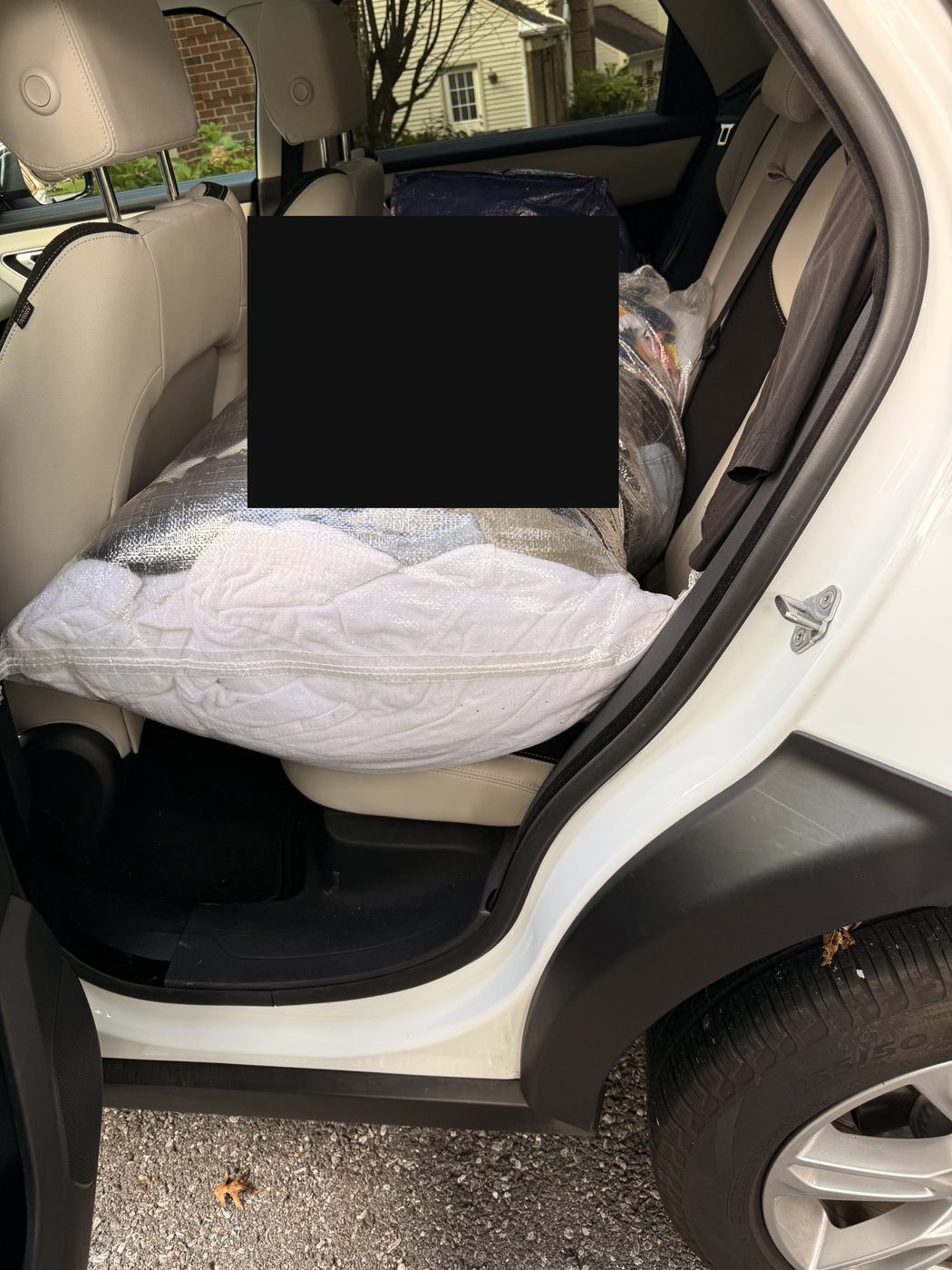 Wrapped bags of donated clothing and essentials packed across the back seat of an SUV